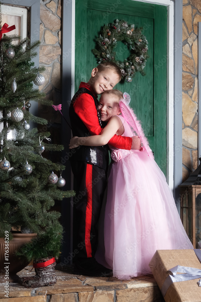 Fototapeta premium Brother and sister are hugging at the door of the house at Christmas