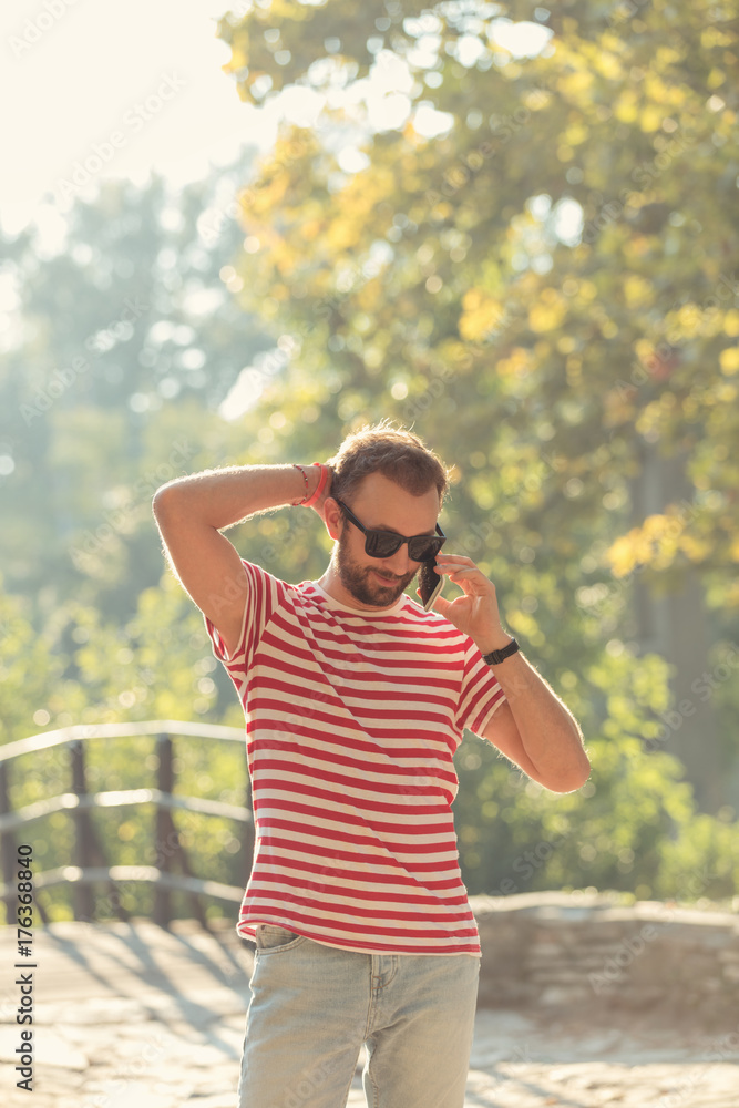 Young man talking on the phone in park. Young man talking on the phone in park.