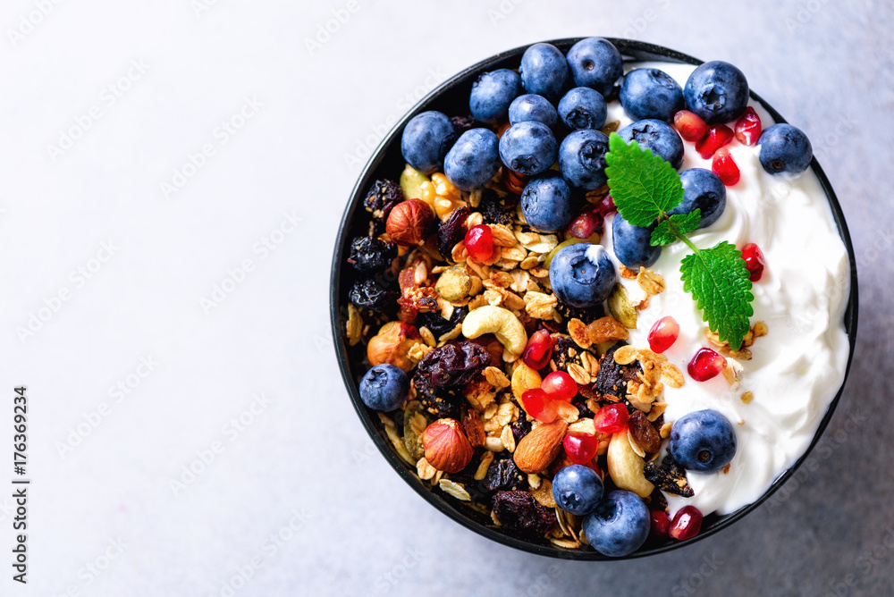 Tasty homemade granola, yogurt, fresh organic berries, pomegranate, mint on grey concrete background with copy space, top view. Tasty homemade granola, yogurt, fresh organic berries, pomegranate, mint on grey concrete background with copy space, top view.