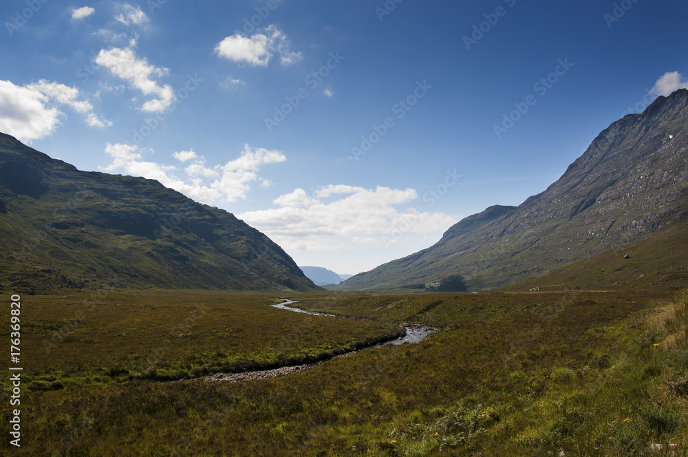 Beautiful widing river along a valley surrounded by mountains in the Highlands of Scotland, United Kingdom; Concept for travel in Scotland