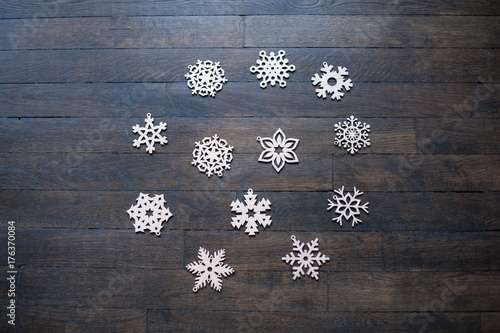 handmade wooden artificial snowflakes laying in a pattern on dark wood background 