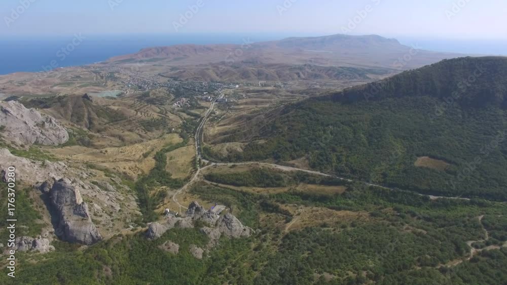 Green forest on mountain ridges, aerial view / AERIAL: Mountain landscape with blue sea in the distance Green forest on mountain ridges, aerial view / AERIAL: Mountain landscape with blue sea in the distance