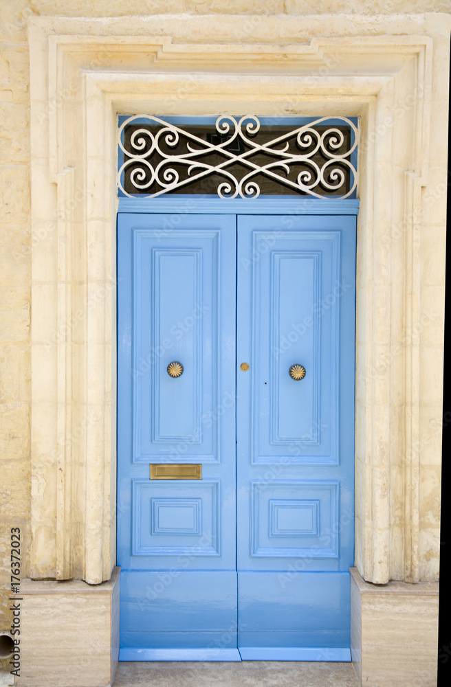 Light blue wooden entrance door with ornated sign and knocker 