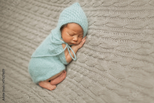 Bild auf Leinwand Tiny baby in mint dress sleeps on the woolen blanket