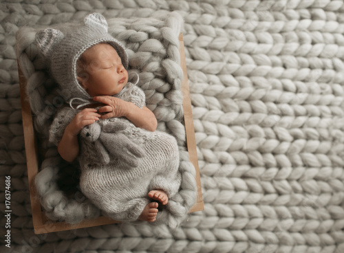 Tiny baby in grey clothes sleeps on woolen blanket