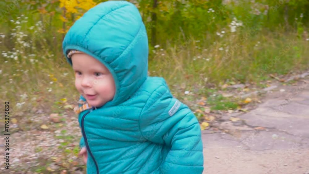 One ear old boy runs in the autumn park and smiles slow motion. gimbal One ear old boy runs in the autumn park and smiles slow motion. gimbal