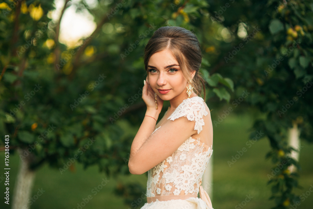Young girl in wedding dress in park posing for photographer. Sunny weather, summer. Young girl in wedding dress in park posing for photographer. Sunny weather, summer.