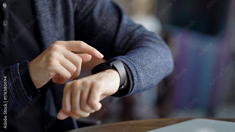 Crop shot of man checking time. Crop shot of male using smartwatch while sitting in cafe.