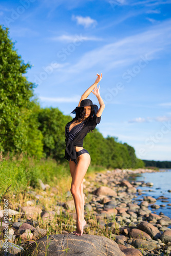 full length portrait of beautiful model in bikini posing on rocky beach