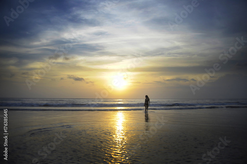 young woman on sea landscape sunset horizon with amazing sun and dramatic orange sky