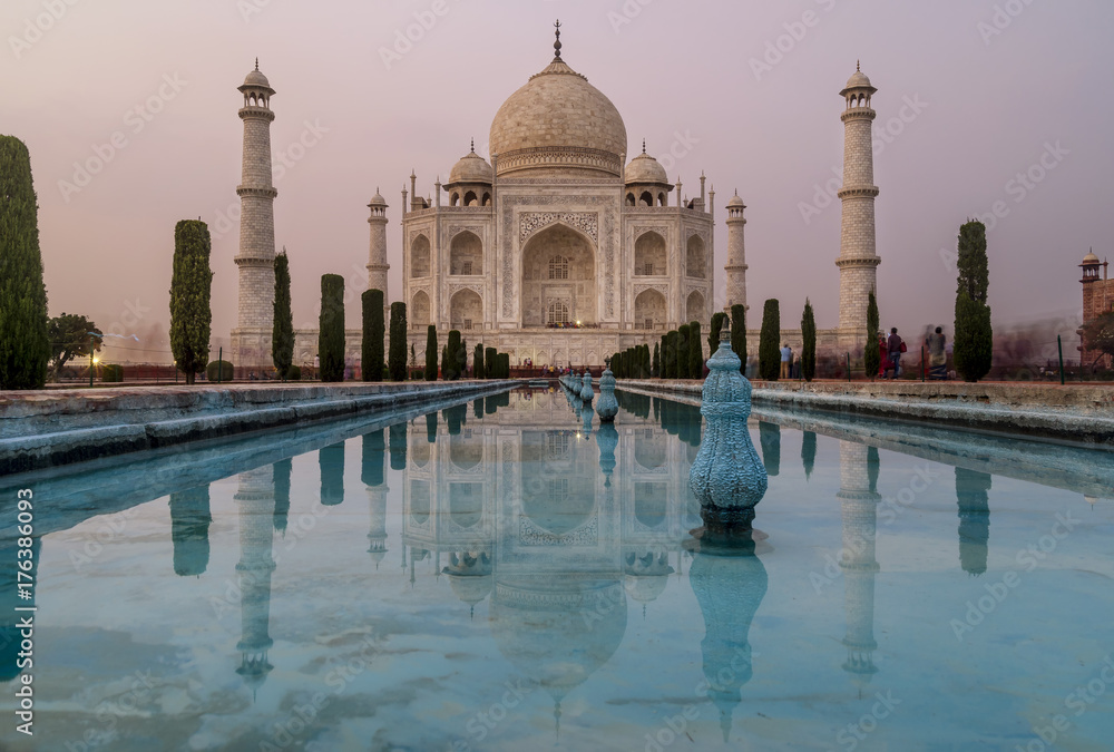 Obraz premium The famous Taj Mahal, Agra, India, is reflected in the water of the gardens' pools at dusk