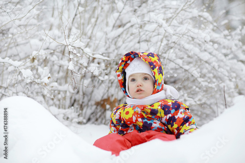 Little cheerful girl on a winter walk in the snow