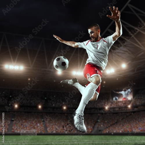Soccer player performs an action play and beats the ball on a professional stadium. Player wears unbranded sport uniform. © Alex