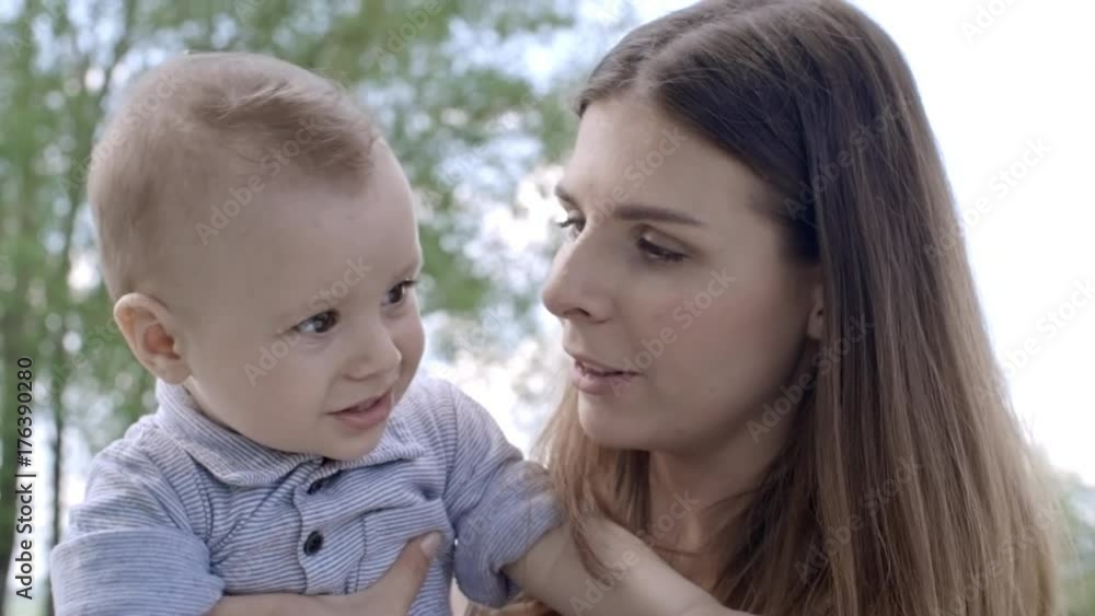 Affectionate mother talking and kissing fussy little boy while spending time outside on summer day Affectionate mother talking and kissing fussy little boy while spending time outside on summer day
