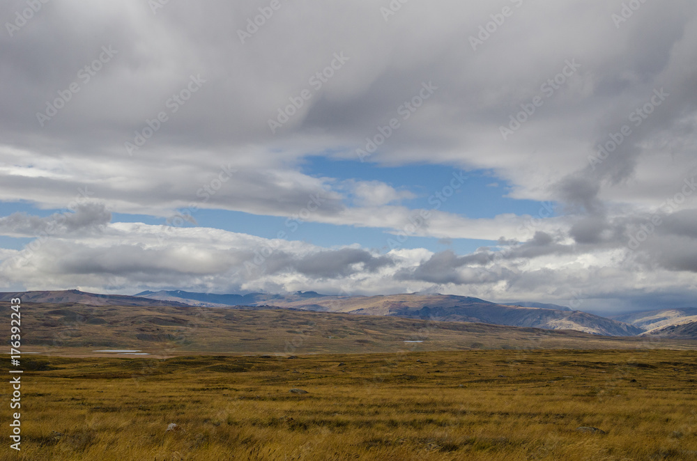 Wildlife Altai. The river, mountains and sky with clouds in summer Wildlife Altai. The river, mountains and sky with clouds in summer