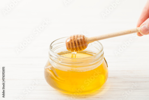Wooden spoon for honey in hand on white