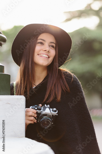 Beautiful woman holding camera while standing outdoors