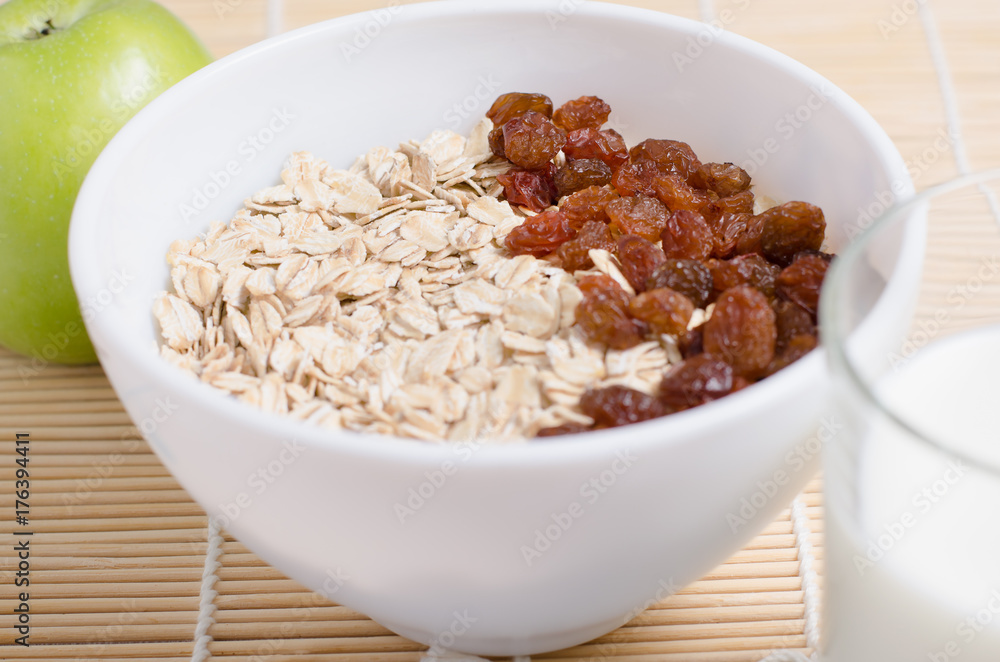 Oatmeal with raisins on the tablecloth from bamboo. Milk, green Apple Oatmeal with raisins on the tablecloth from bamboo. Milk, green Apple
