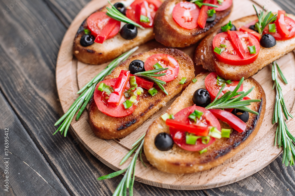 appetizer of toast with tomatoes, olives, paprika and greens, decorated with rosemary