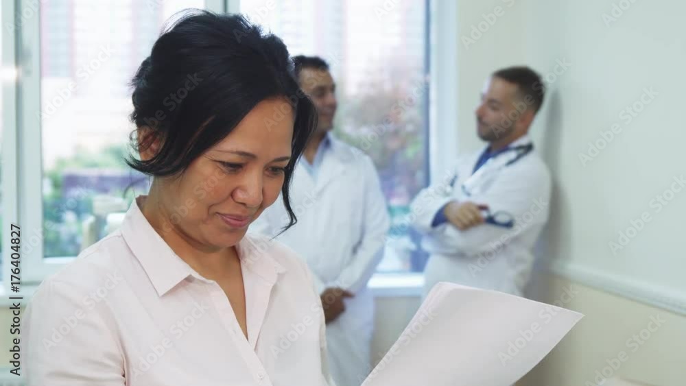 The patient holds the results of her medical research. She carefully reads it. She is very happy and smiling. She shows thumbs up The patient holds the results of her medical research. She carefully reads it. She is very happy and smiling. She shows thumbs up