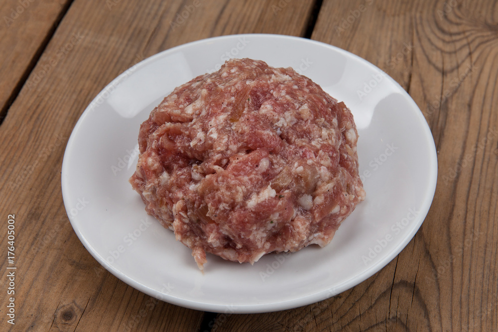 raw ground meat on a white plate on a wooden table raw ground meat on a white plate on a wooden table