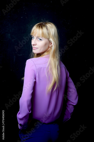 Beautiful young girl posing by the dark wall