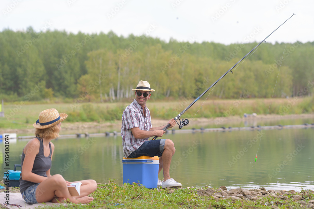 happy couple fishing on the banks of the pond happy couple fishing on the banks of the pond