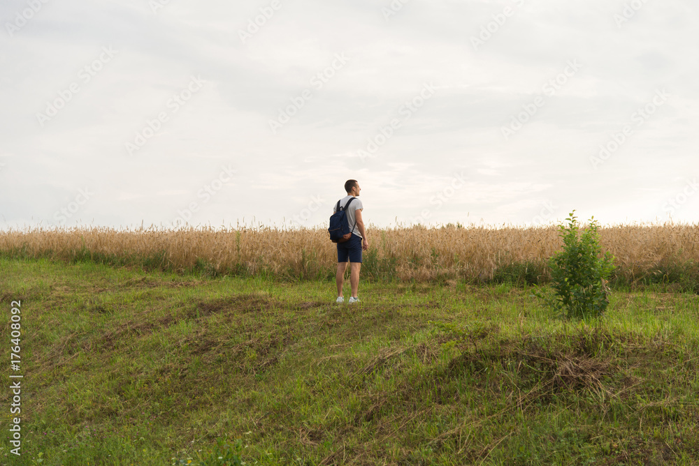 A man standing on the grass looking towards the sun