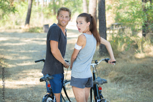 young surprised couple with bicycles in forest