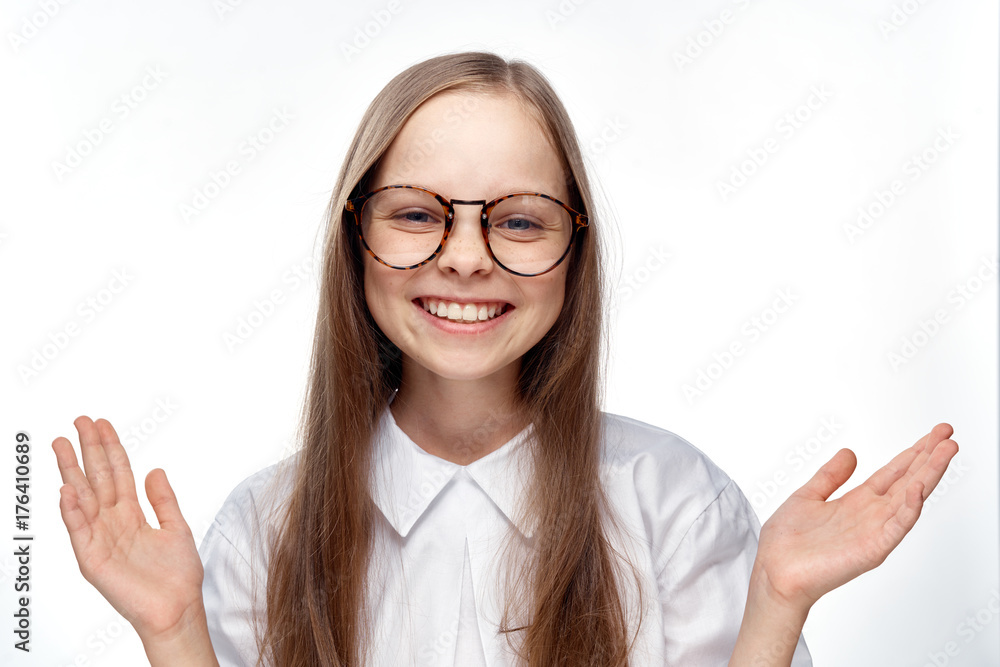 1657249 the little girl smiles and laughs with glasses on a white background and points to the empty space 1657249 the little girl smiles and laughs with glasses on a white background and points to the empty space