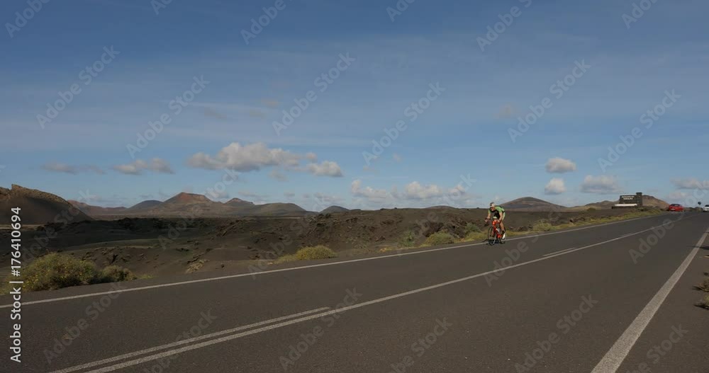 A Road Cyclist Peddles along a road with Volcanos in the background. A Road Cyclist Peddles along a road with Volcanos in the background.