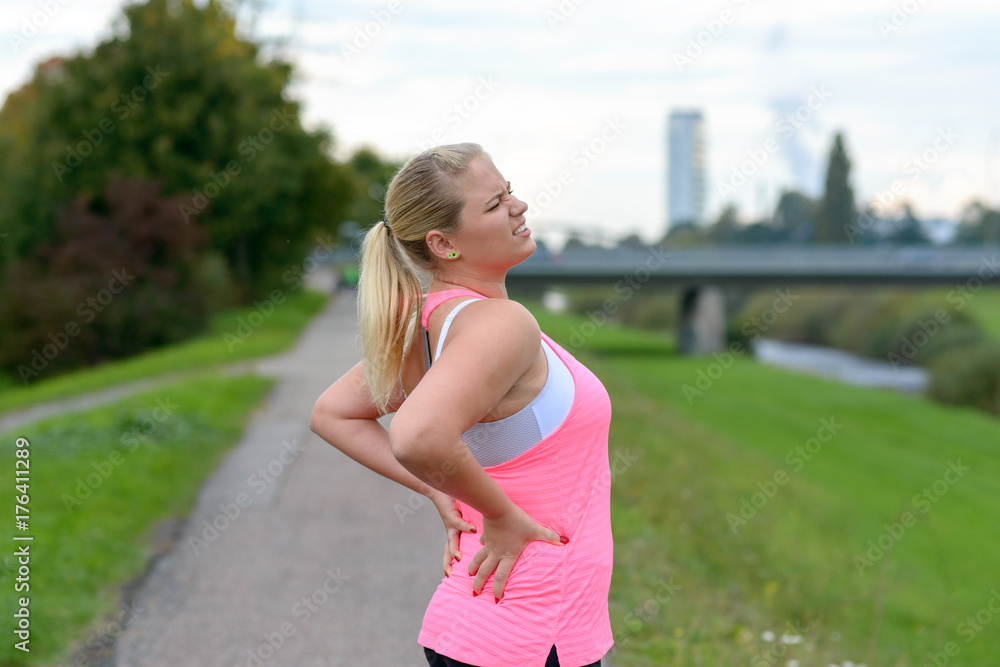 Young blonde woman holding her painful back Young blonde woman holding her painful back