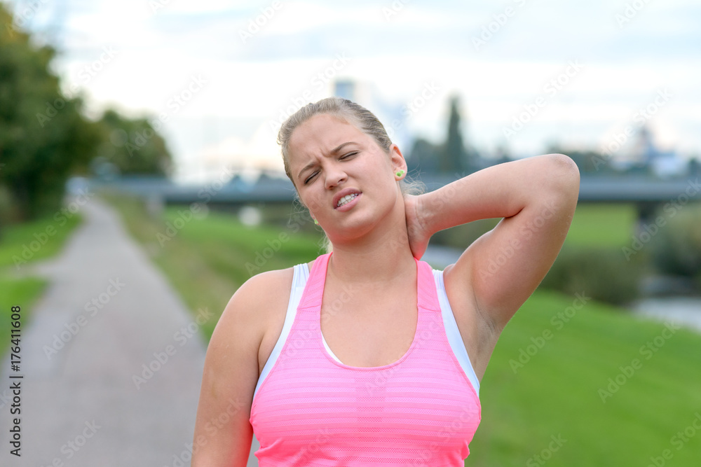 Young blonde woman holding her painful neck Young blonde woman holding her painful neck