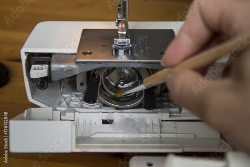 cleaning and preparation of sewing machine.A woman uses a brush to clean the inside of the sewing machine from dust