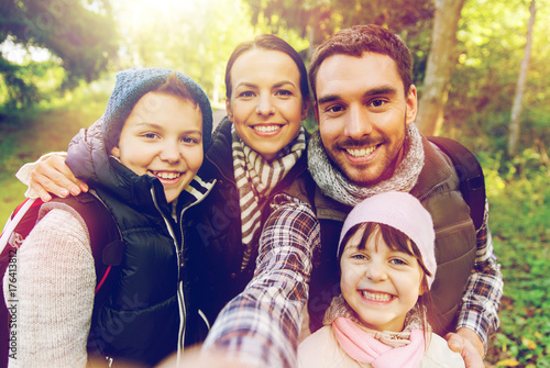 family with backpacks taking selfie and hiking