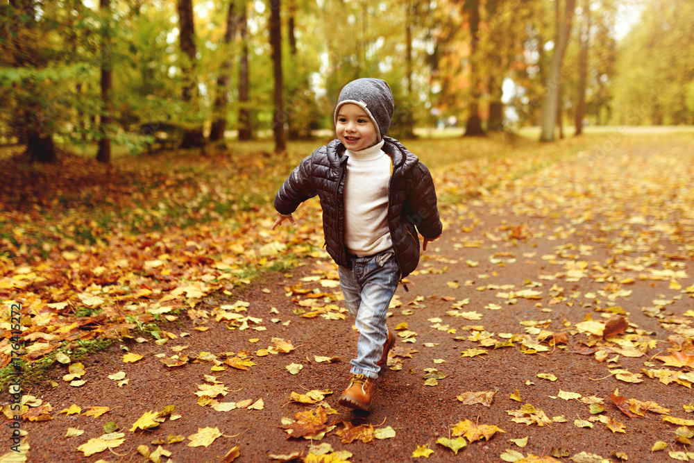 young boy running in autumn park