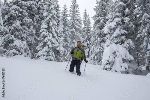 Happy traveler, with backpack, is walking in deep snow