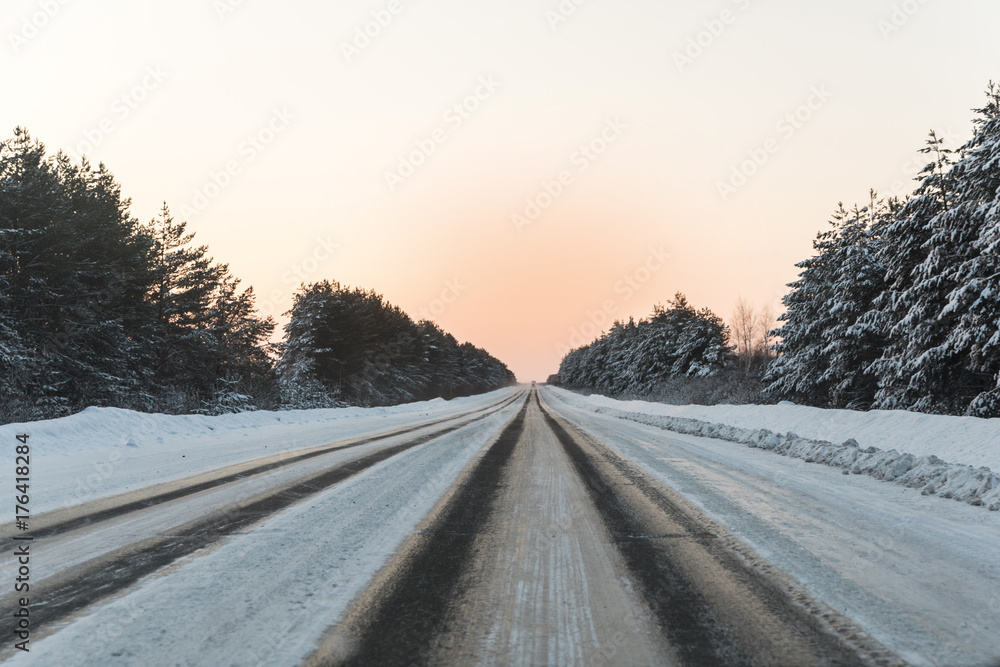 winter road with ice on the asphalt, trees under snow during the winter frost winter road with ice on the asphalt, trees under snow during the winter frost