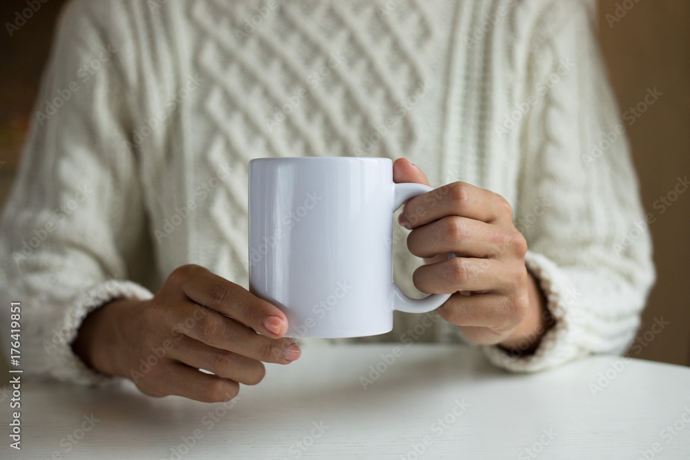 Hands are holding a cup. It's a time of cold season to wear a soft warm white pullover and to feel comfortable, relaxed and healthy. Hands are holding a cup. It's a time of cold season to wear a soft warm white pullover and to feel comfortable, relaxed and healthy.