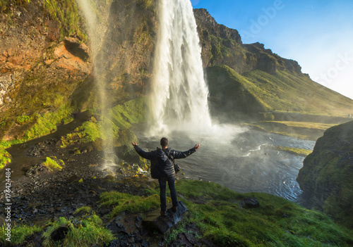 Tourist standing in front of Seljalandsfoss one of the best known waterfalls in southern Iceland, Seljalandsfoss , Iceland