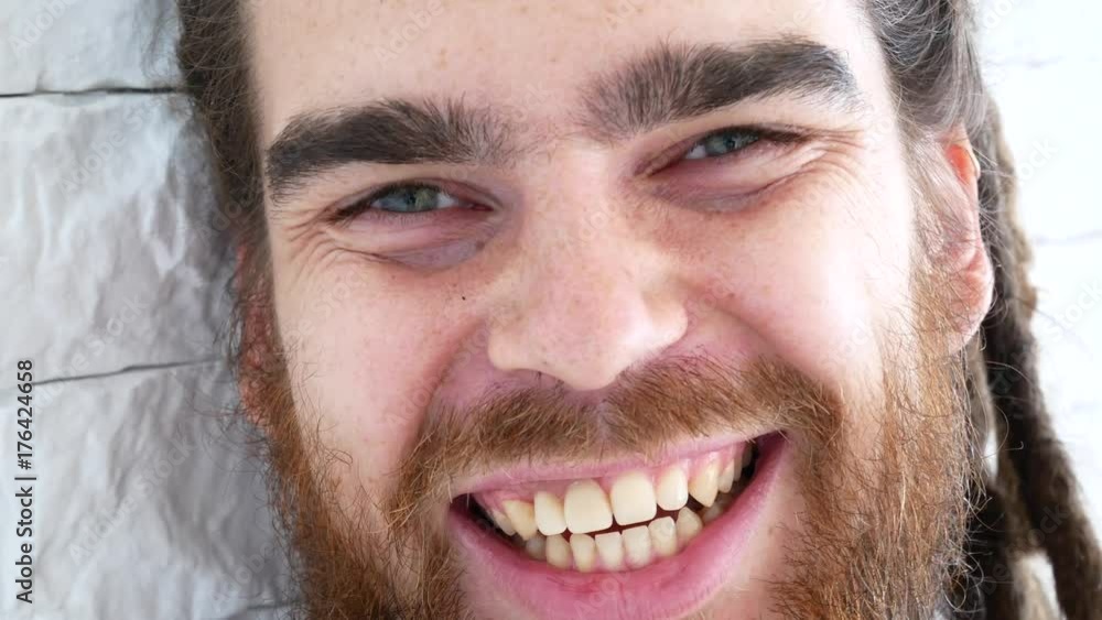 The man is laughing. The guy smiles, standing near the white brick wall. The man is laughing. The guy smiles, standing near the white brick wall.