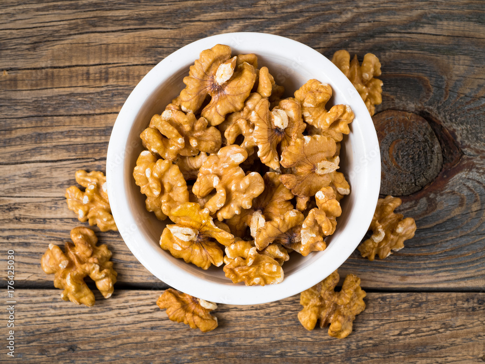 Top view of white cups with walnut, bowls with handful of nuts on a wooden background Top view of white cups with walnut, bowls with handful of nuts on a wooden background