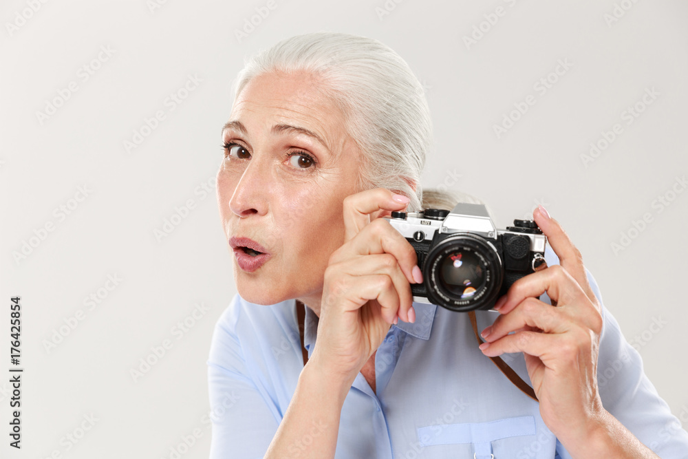 Surprised woman holding retro camera islated over white Surprised woman holding retro camera islated over white