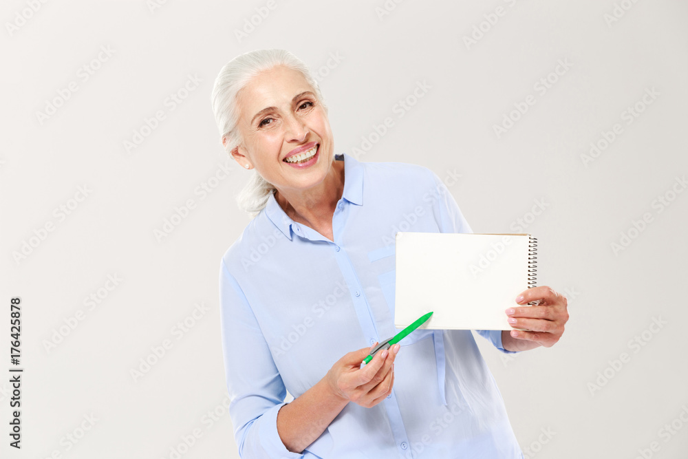 Smiling mature woman showing notebook with copy space for text isolated