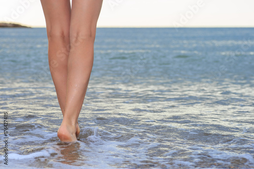 Woman legs, walking on the beach.