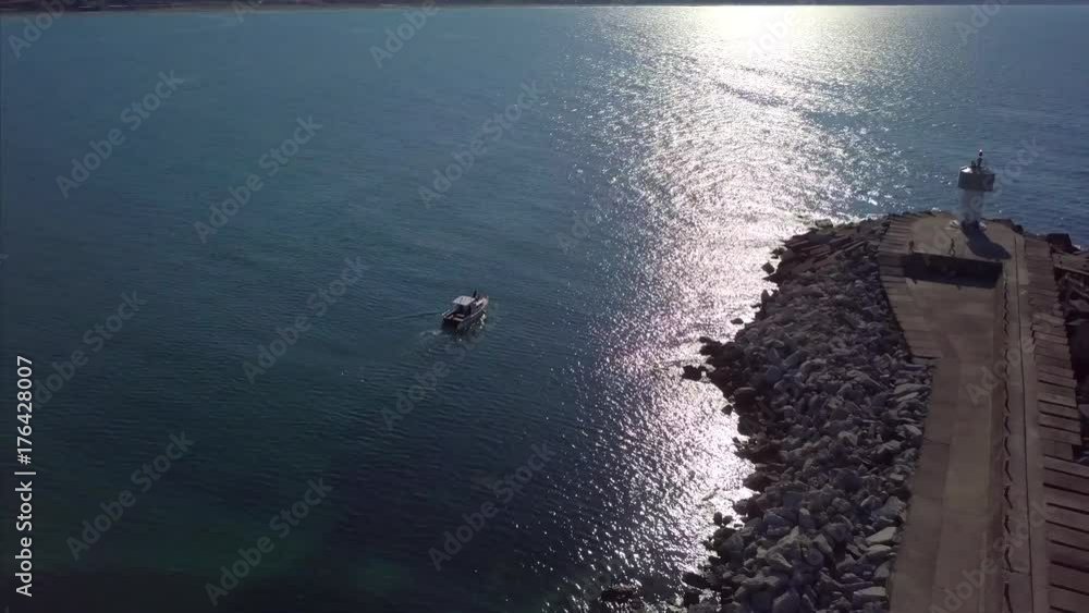 Aerial view of boat and breakwater - tracking shot Aerial view of boat and breakwater - tracking shot