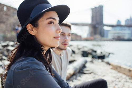 Young couple sitting along the river, Brooklyn, New York