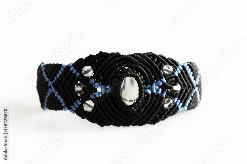 black bracelet on the hand of waxed thread, plastic beads and moonstone in the technique of macrame.