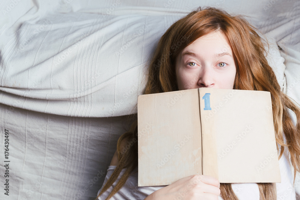 Woman with ginger dreadlocks is reading a book with the blue number 1 sign on the cover