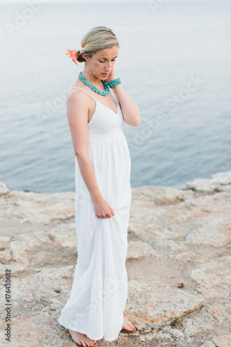 Blond Woman Wearing White Sun Dress on Rocky Coast photo